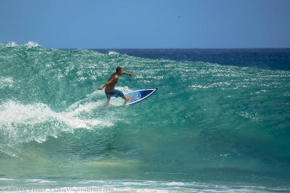 Imagem de um surfistas no topo da onda em Fernando de Noronha.